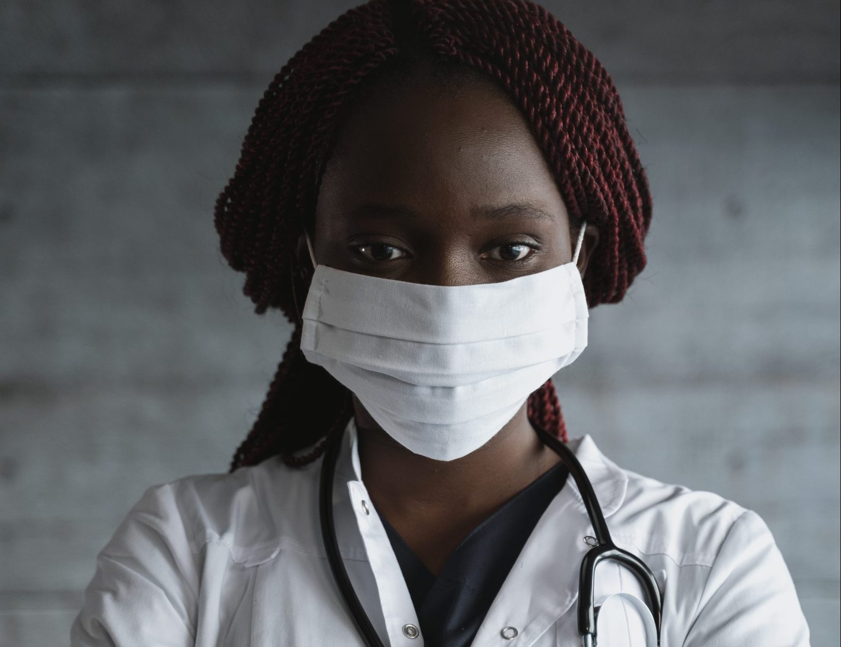 A woman in white lab coat and face mask