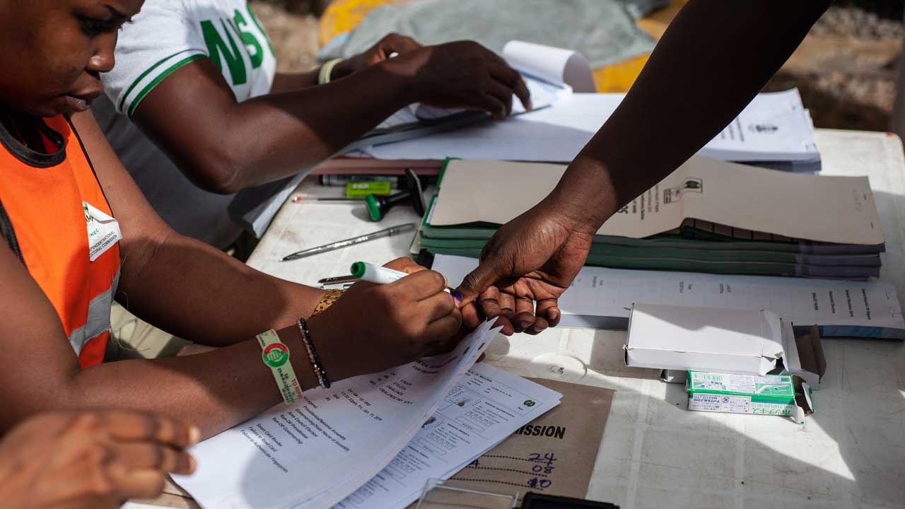 A woman holding a paper while a hand is holding it in Nigeria local election