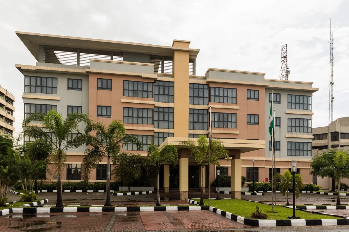 Protea Hotel Select building with palm trees and the Nigerian flag flying at the entrance