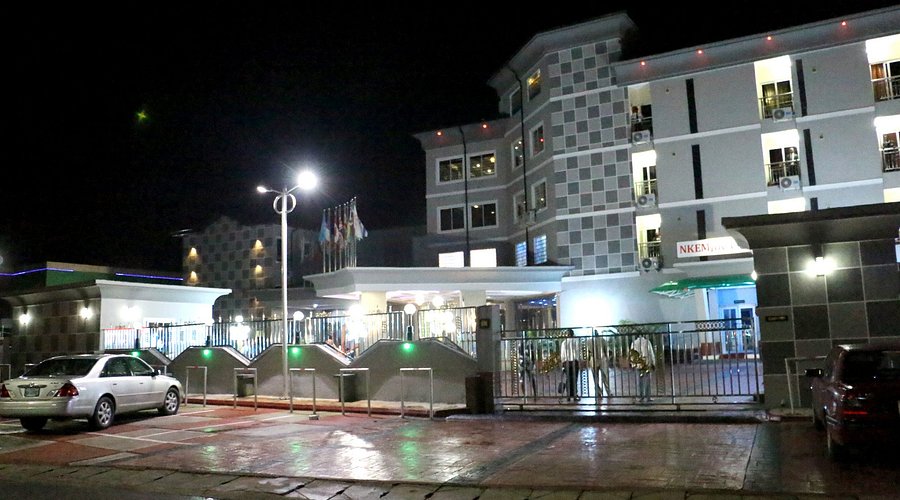 The All Seasons hotel entrance at night with bright lights, wet pavement, and parked cars