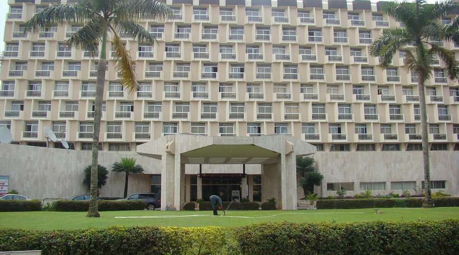 Front view of Imo Concorde hotel with uniform windows, green landscaping, and a worker on the lawn